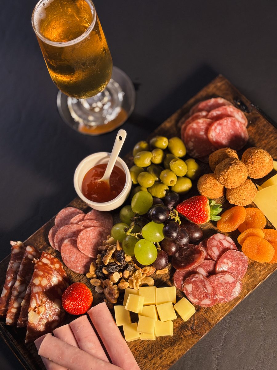 Tabla de fiambres, quesos y frutas con una cerveza