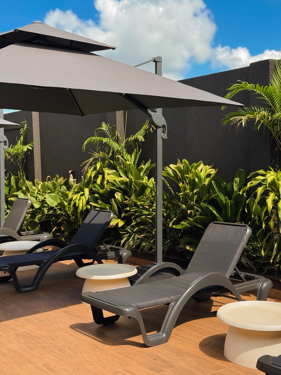 Reposeras bajo la sombrilla con jardín tropical